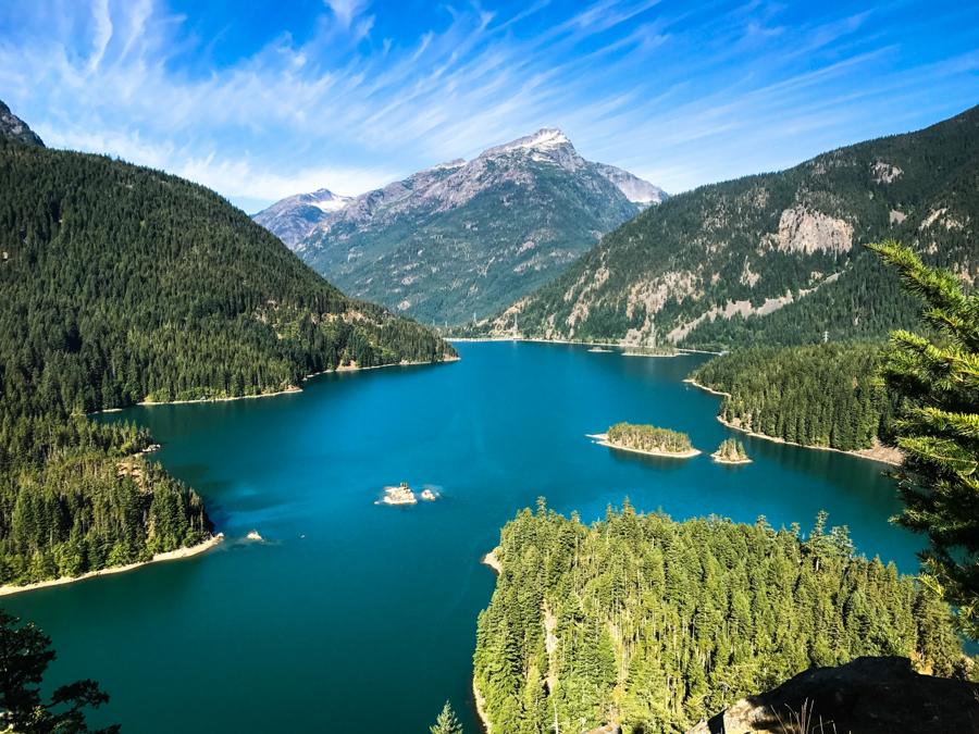 Turquoise lake winding between forested mountains under a blue sky